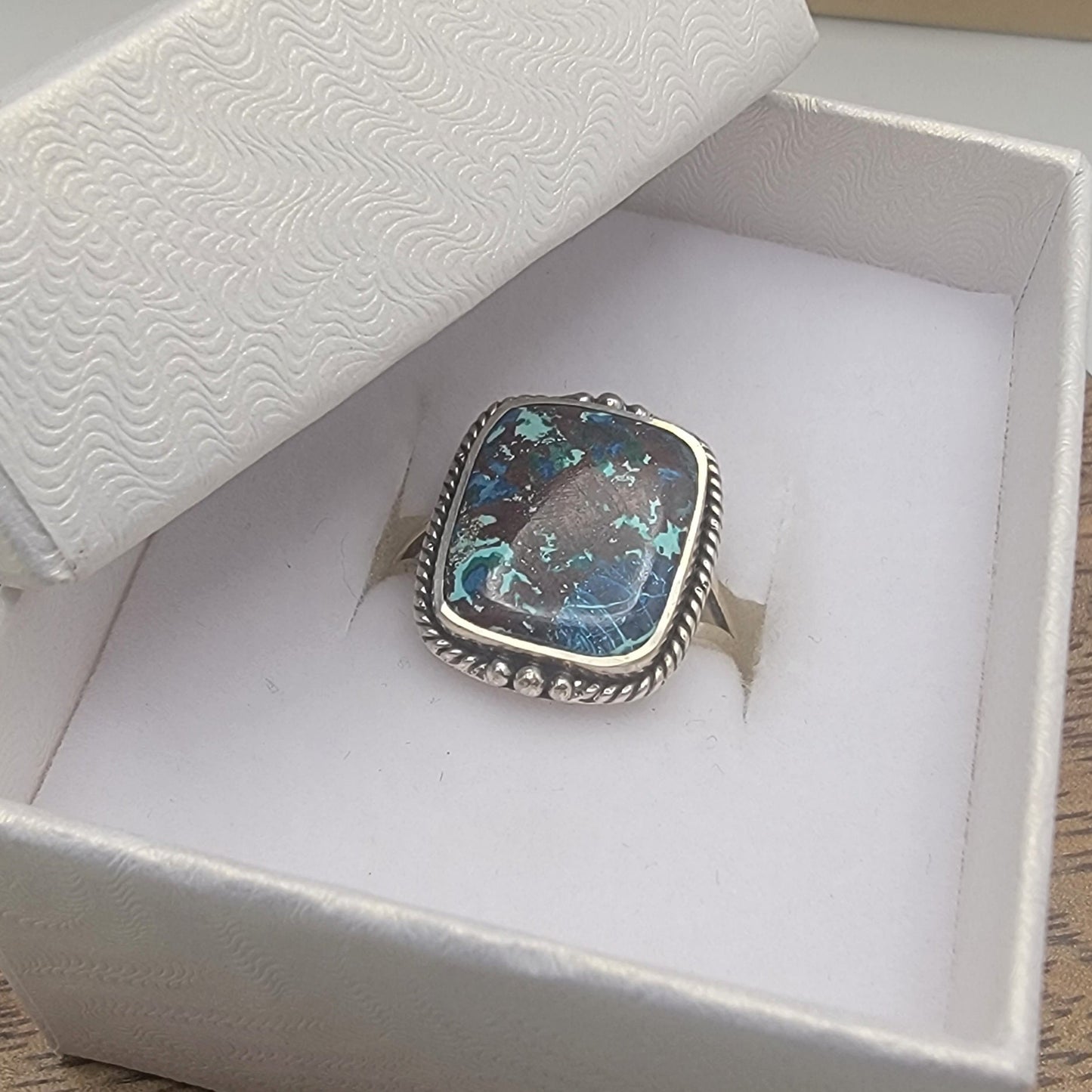 Silver ring with a colorful stone in a white box