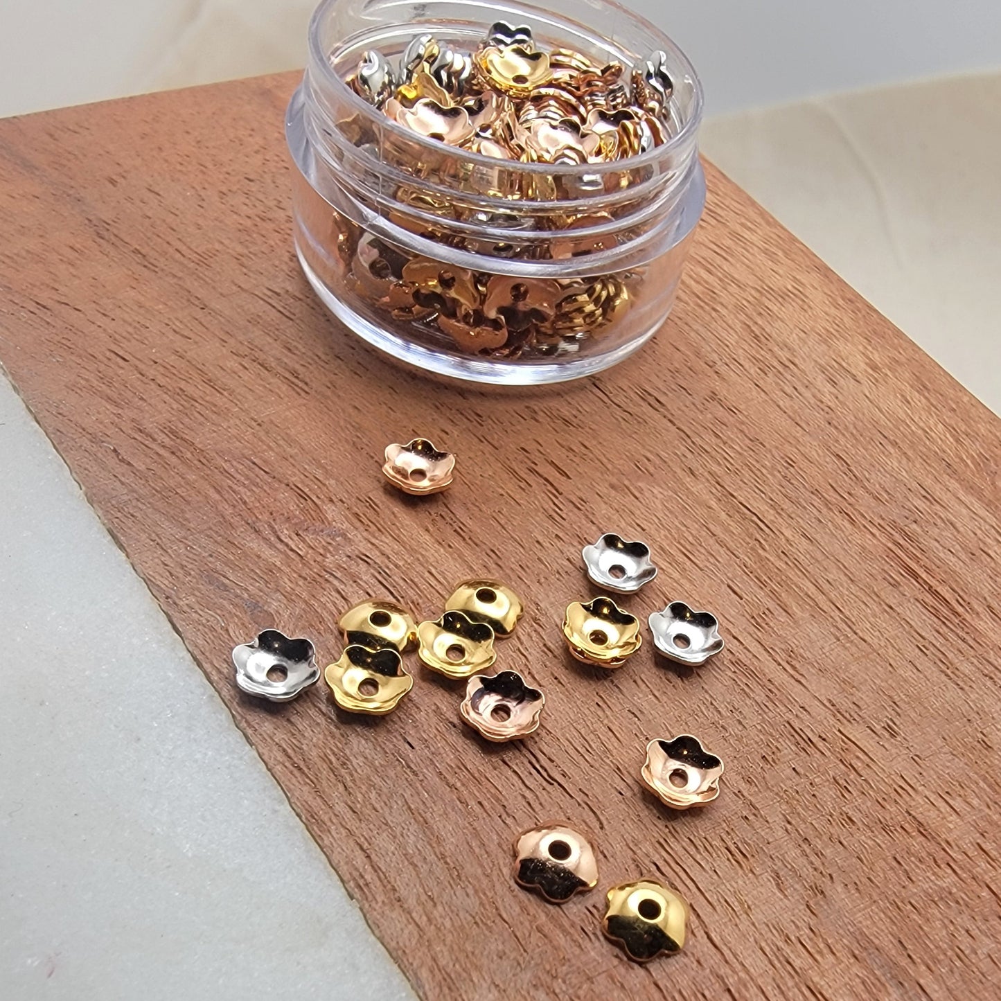 Gold and silver embellishments on a wooden board with a clear container.