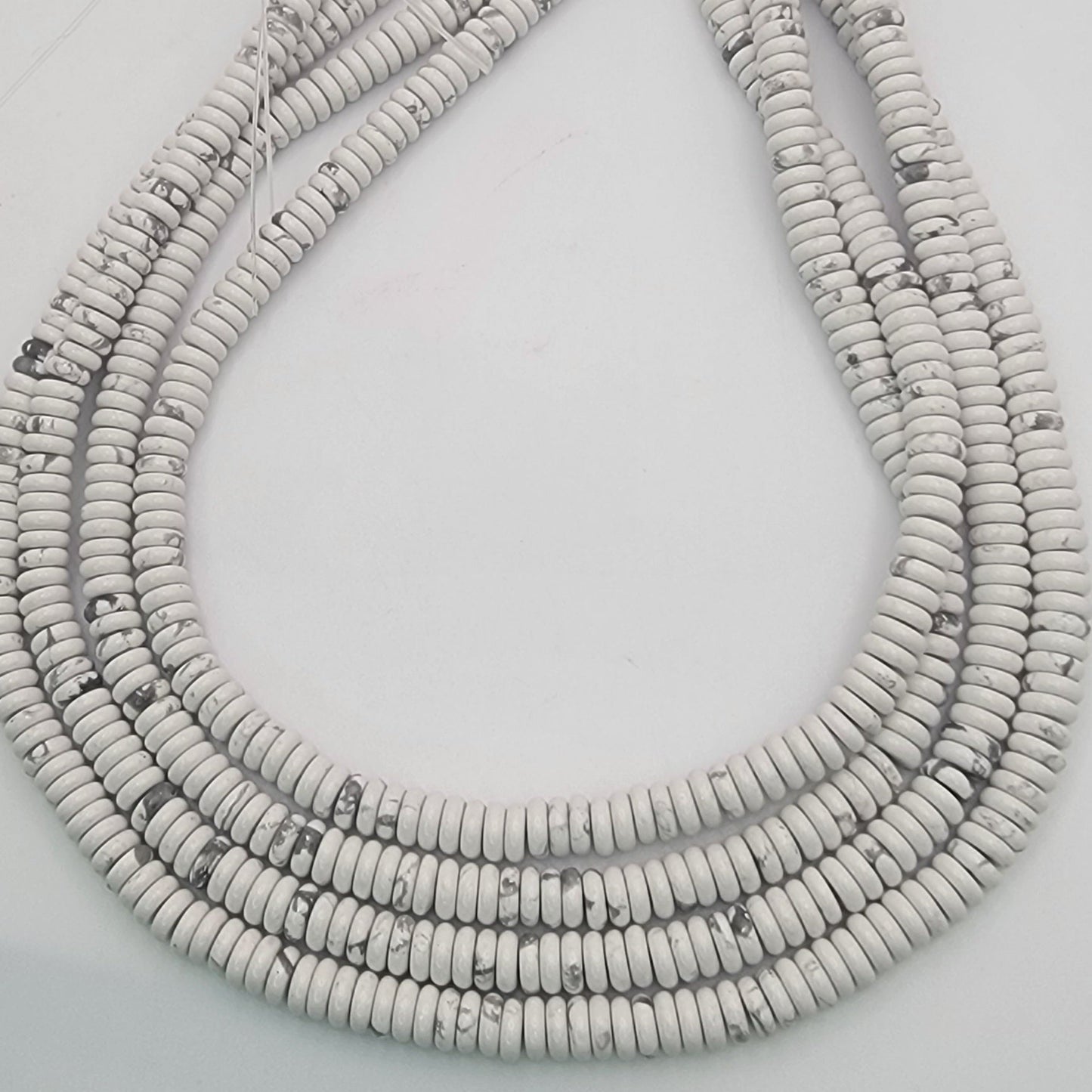 White stone bead strands on a light gray background