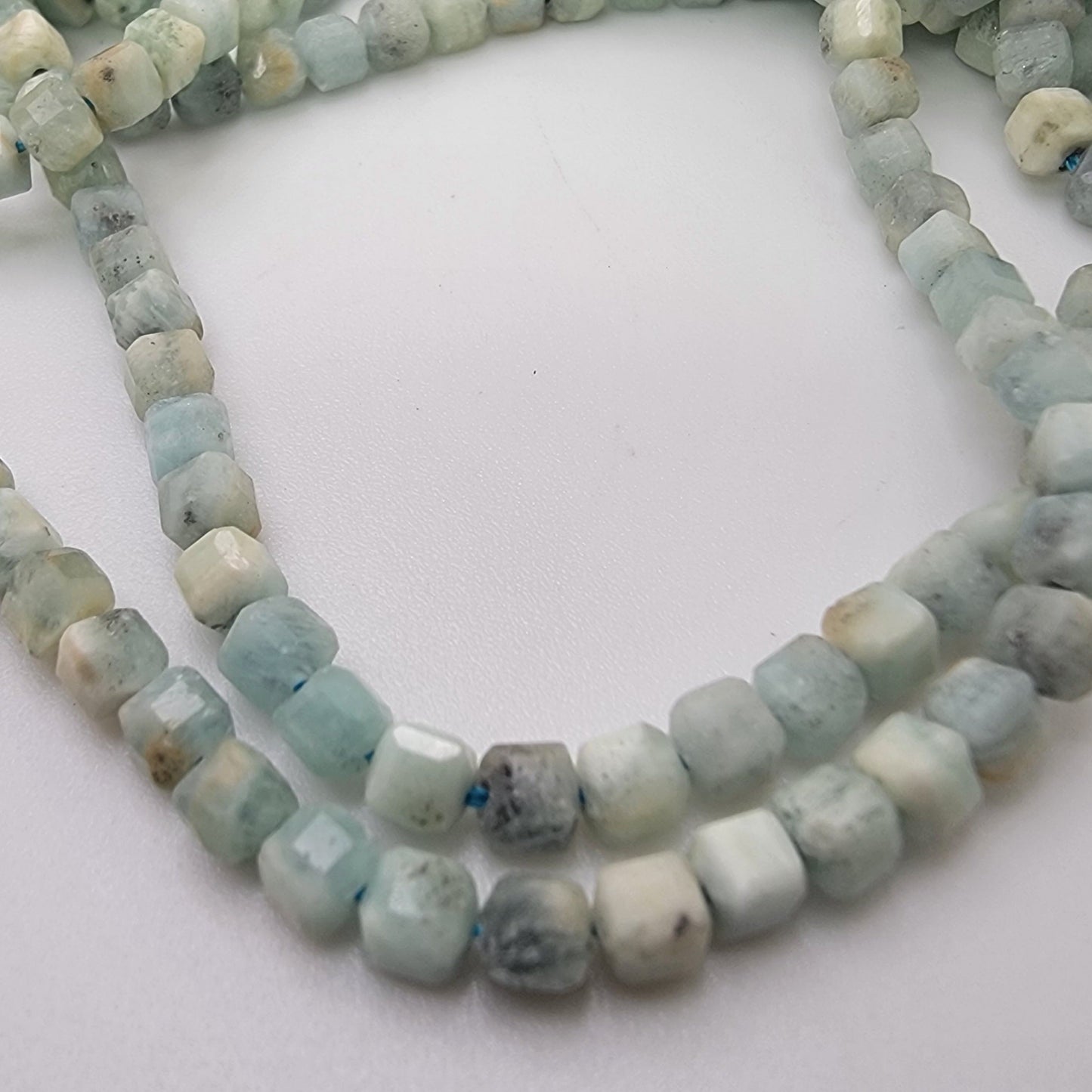 String of light blue and gray beads on a white background