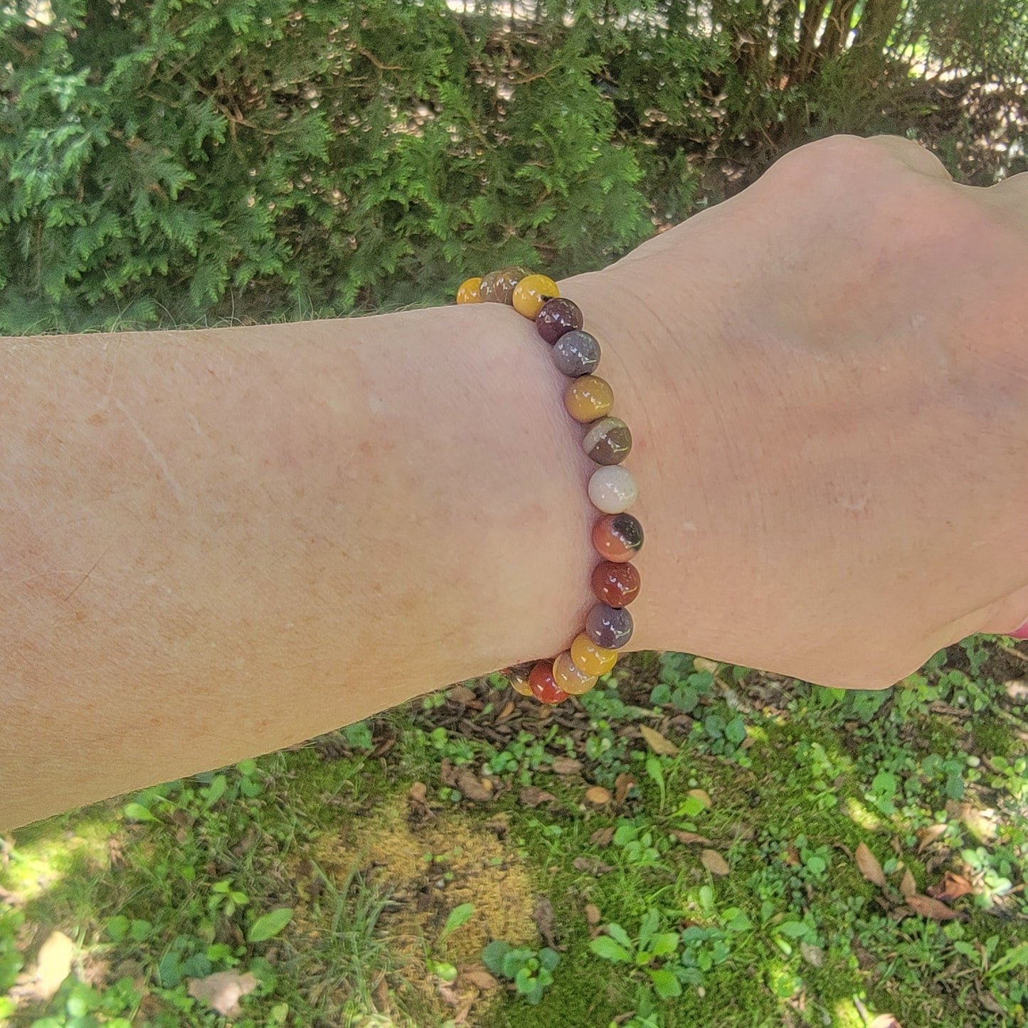 Earth tone beaded bracelet on black branded gift box on a wrist on a natural background