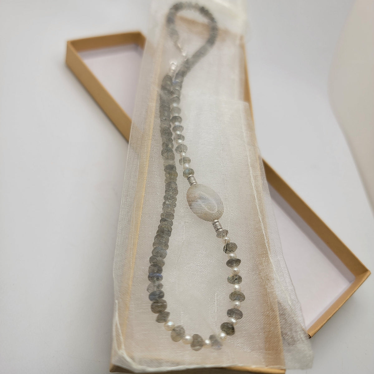 Labradorite and agate focal bead necklace in an organza bag in a cardboard gift box on a white background