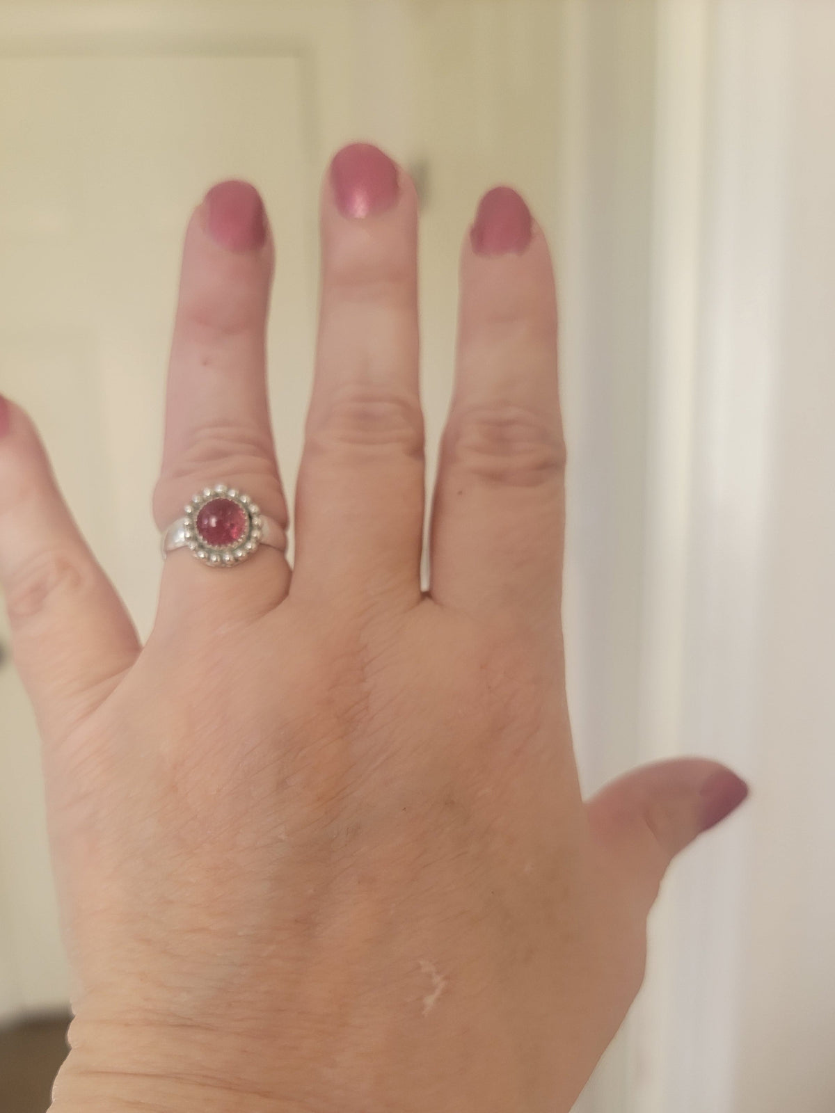 Pink Tourmaline and Sterling silver ring with bead detail around the bezel shown on a hand