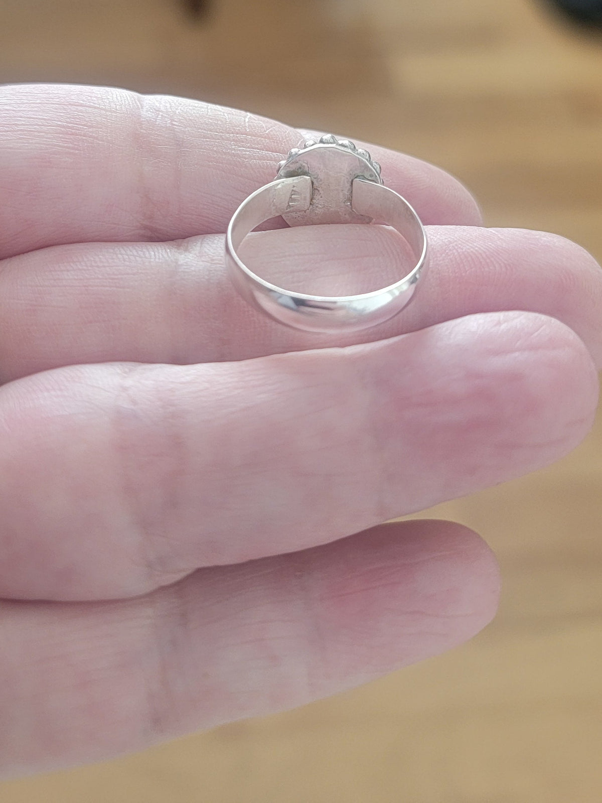 Back view of Pink Tourmaline and Sterling silver ring with bead detail around the bezel being held in a hand