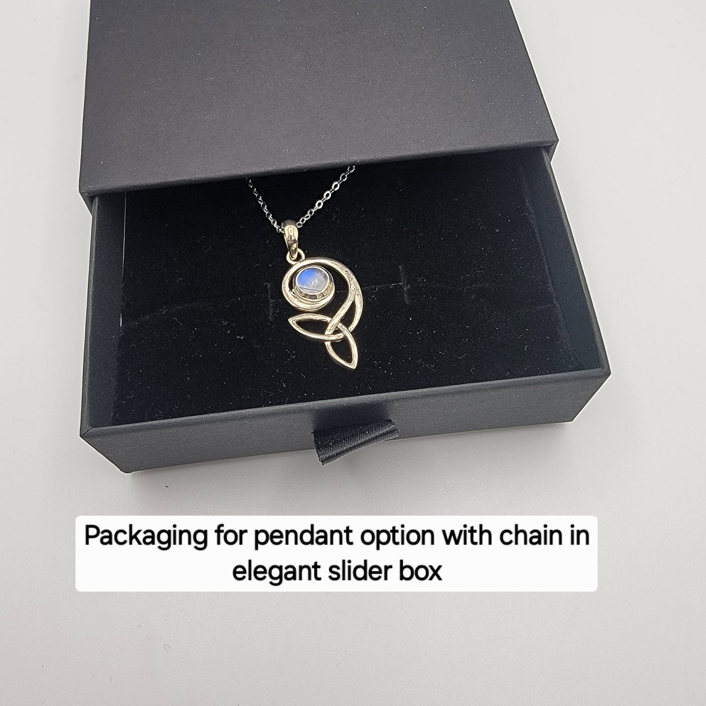Gold pendant necklace with chain in an elegant black slider box on a white background