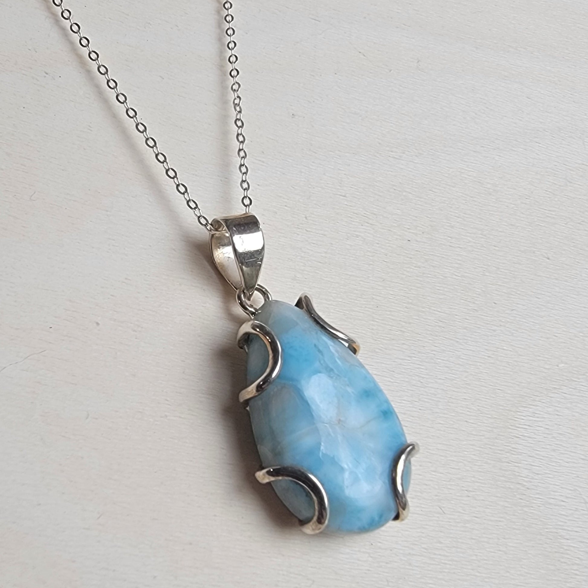 Blue larimar pendant on a silver chain against a light gray background