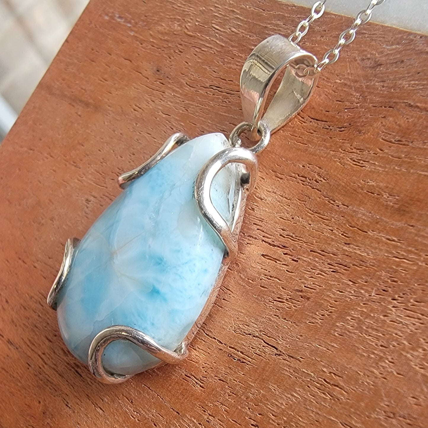 Larimar pendant with silver setting on a wooden surface