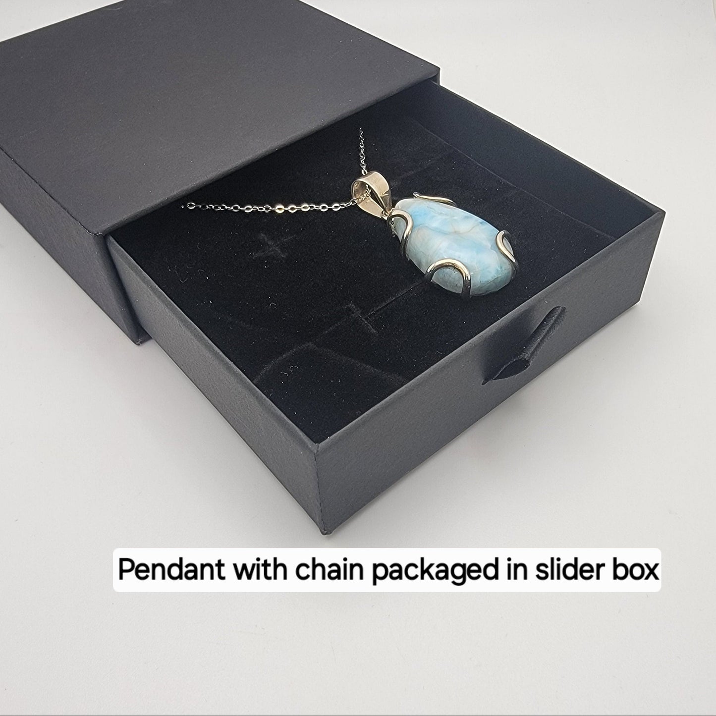 Pendant with chain packaged in a black slider box on a white background