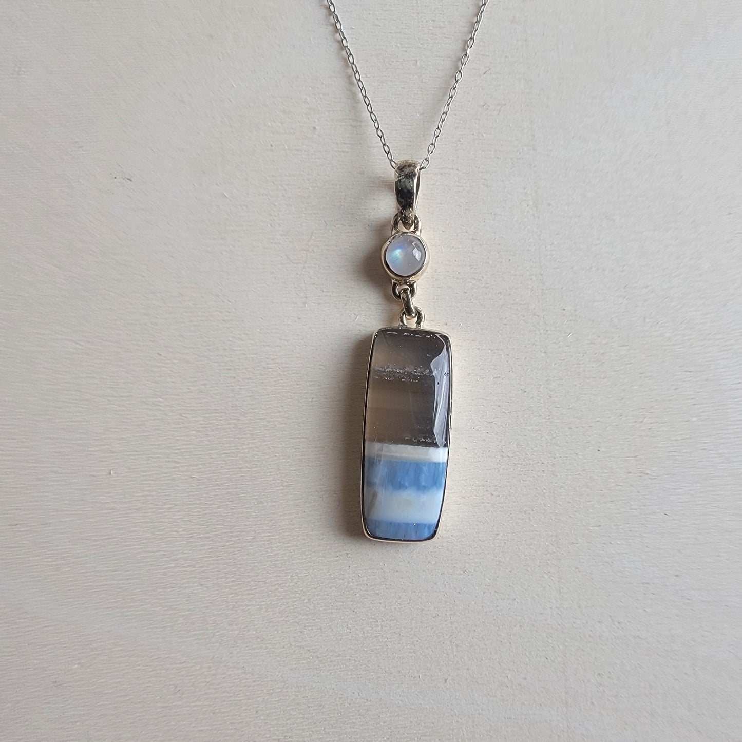 Blue Opal and moonstone necklace with a pendant on a light gray background