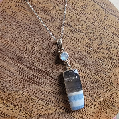 Blue opal and moonstone sterling silver necklace on a wood background