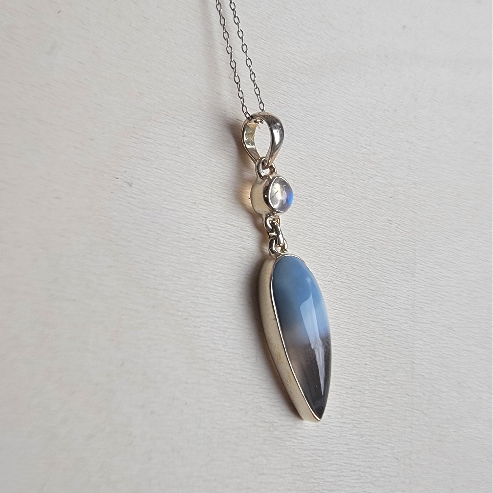 Necklace with a teardrop-shaped blue opal pendant on a light gray background