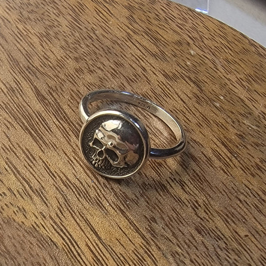 Silver ring with skull design on a wooden surface