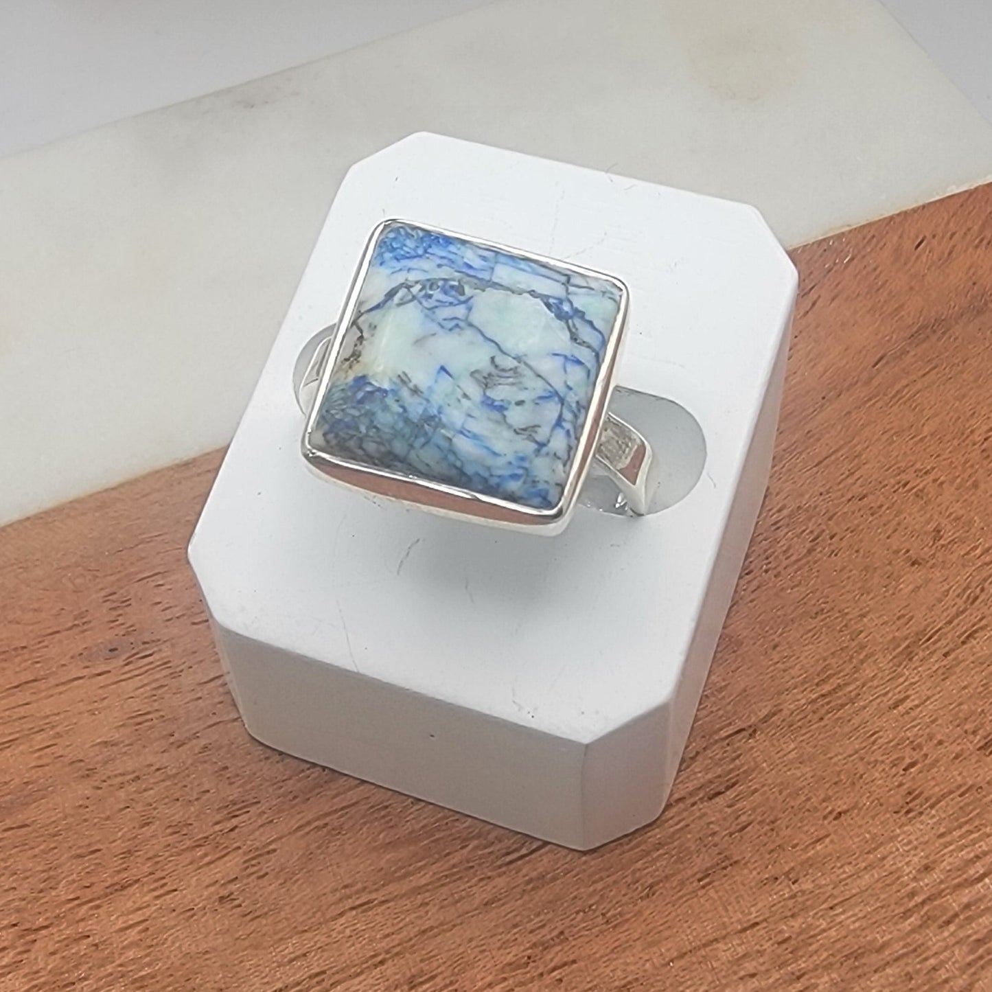 Sterling silver ring with blue cabochon on a white and wood surface 