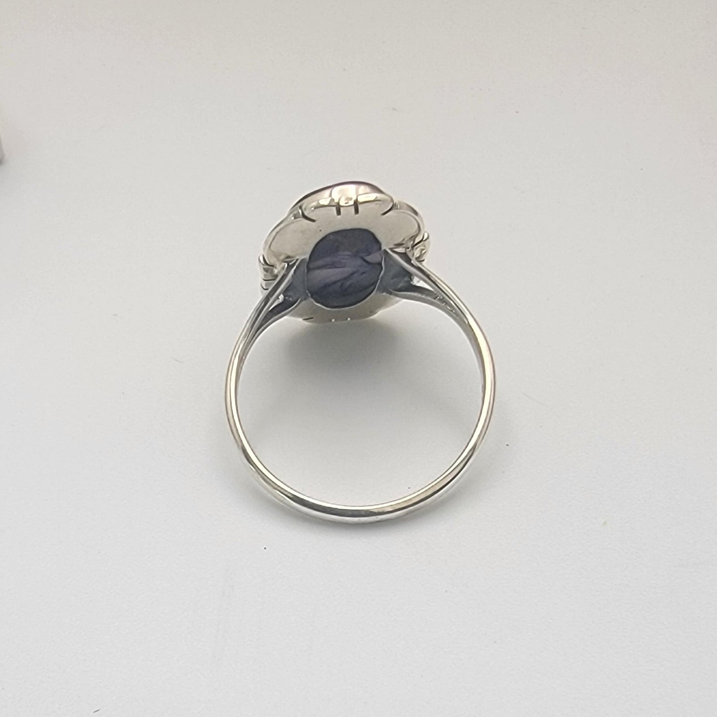Sterling silver ring on a white surface with a gray textured object in the background