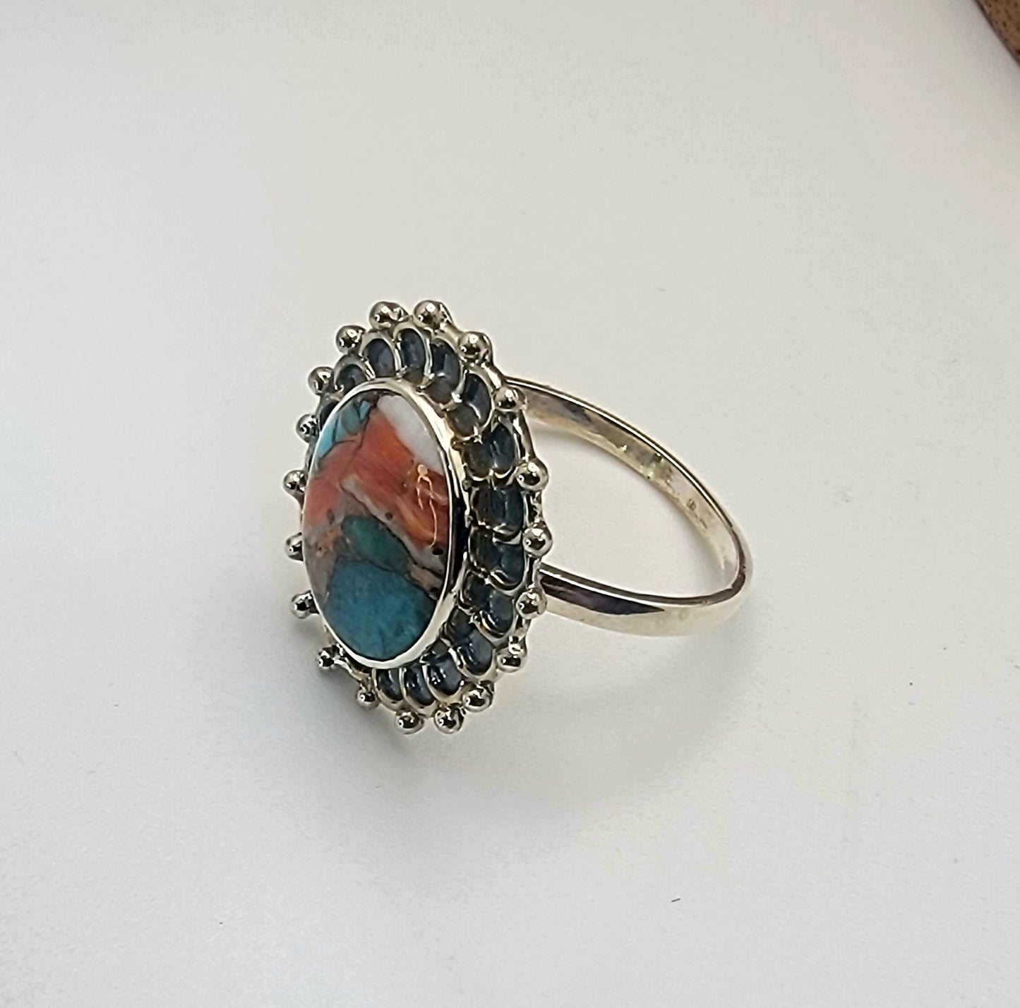 Silver ring with a colorful stone on a white background