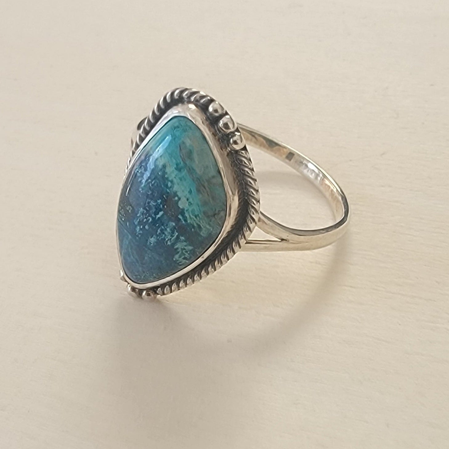 Silver ring with a blue stone on a beige background