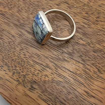 Silver ring with a blue and white patterned stone on a wooden surface