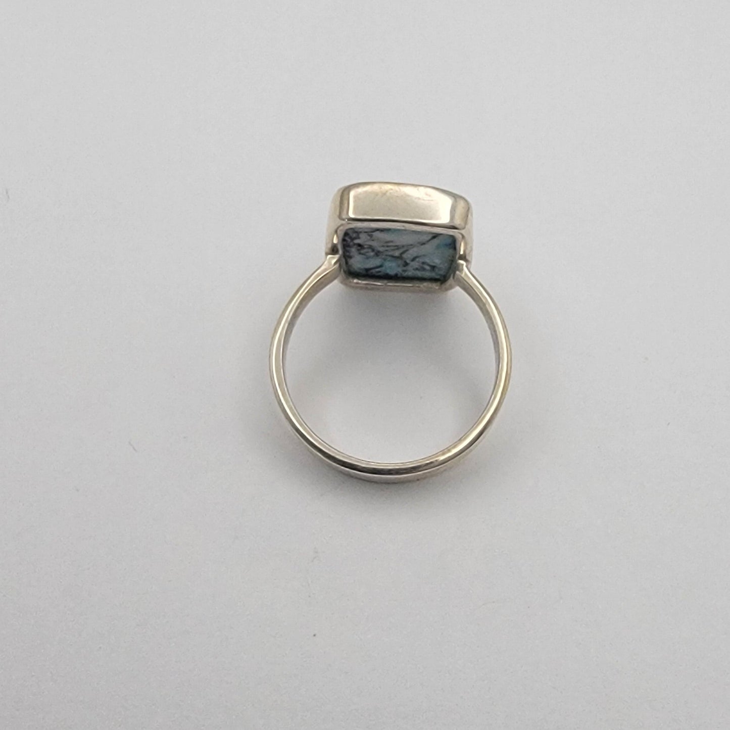 Silver ring with a dark stone on a light gray background