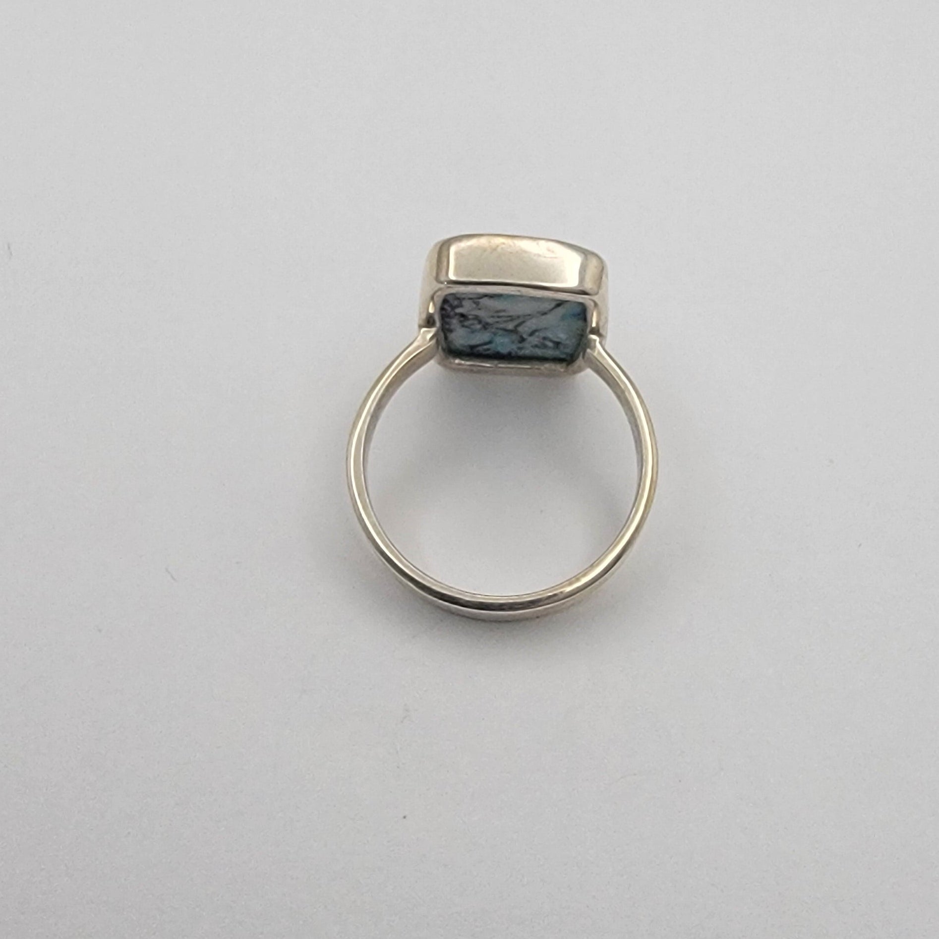 Silver ring with a dark stone on a light gray background