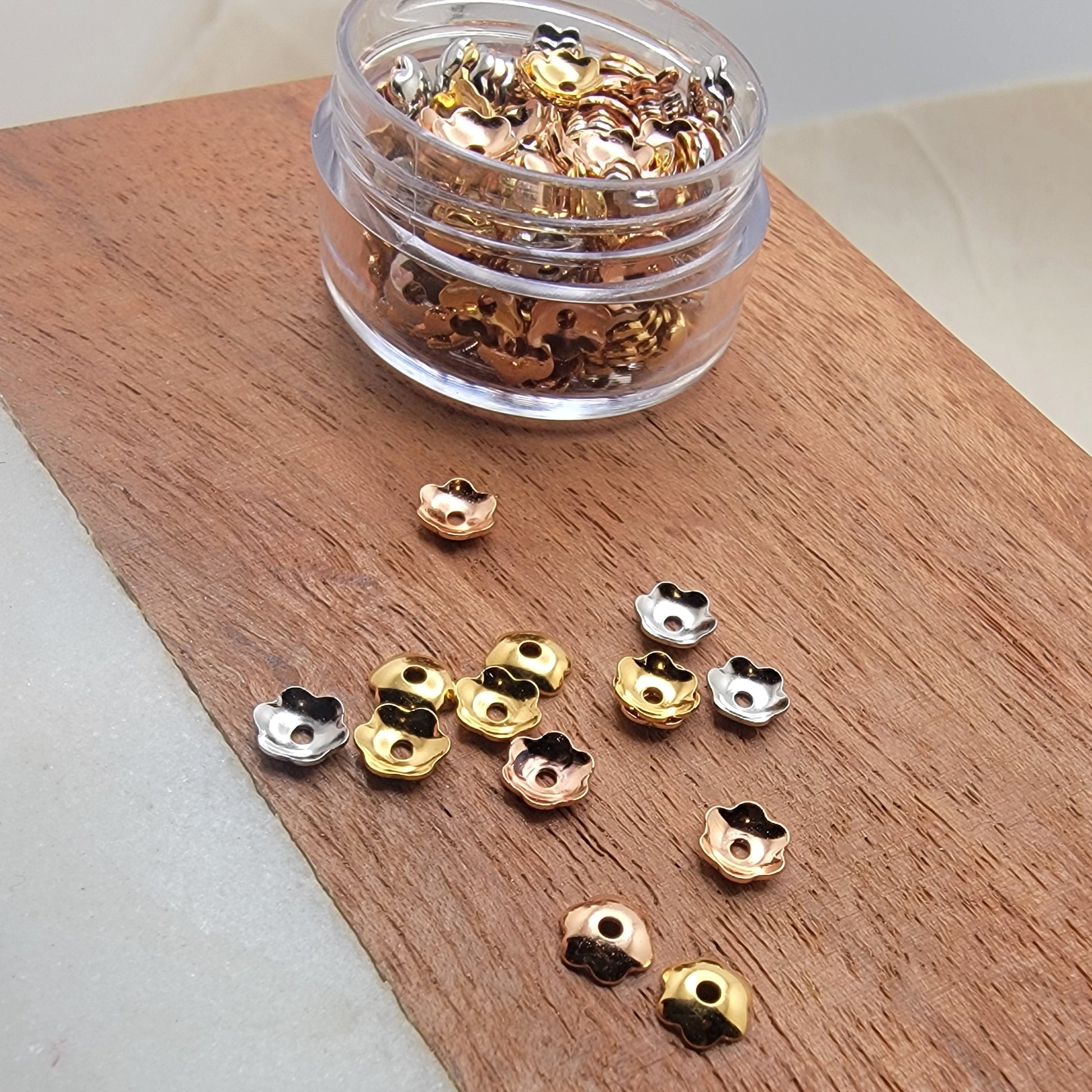 Gold and silver embellishments on a wooden board with a clear container.