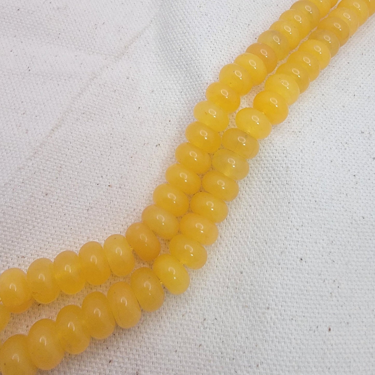 Yellow quartz beads on a white fabric background