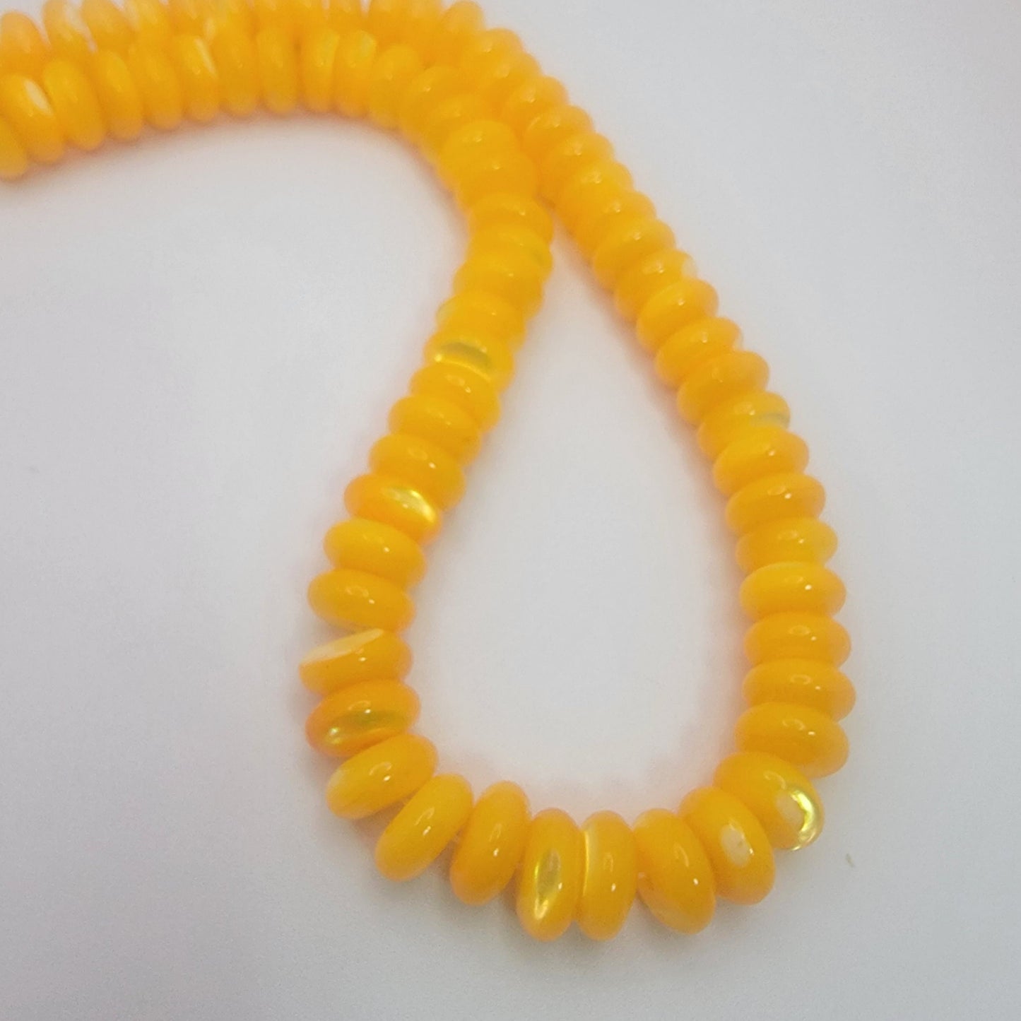 Yellow rondelle shell beads on a neutral background