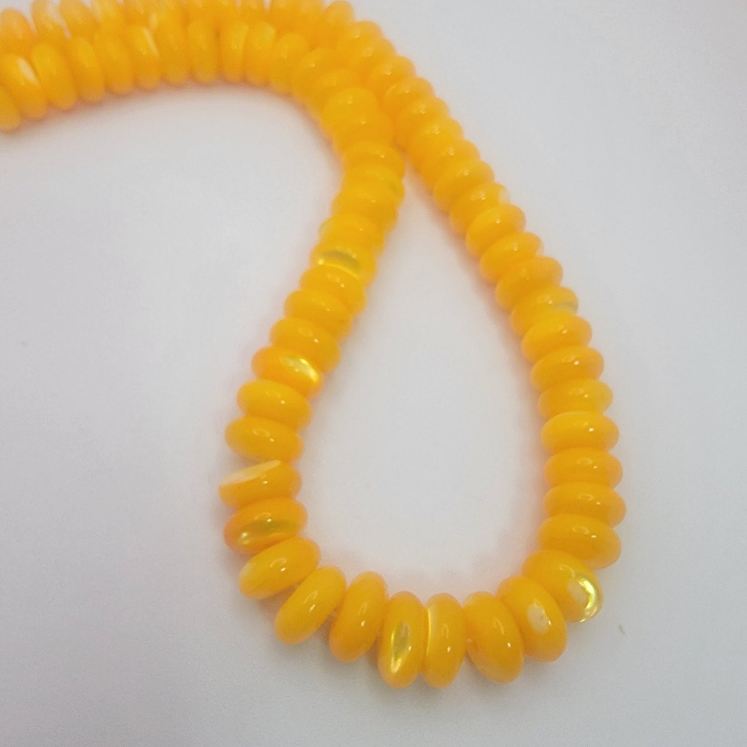 Yellow rondelle shell beads on a neutral background