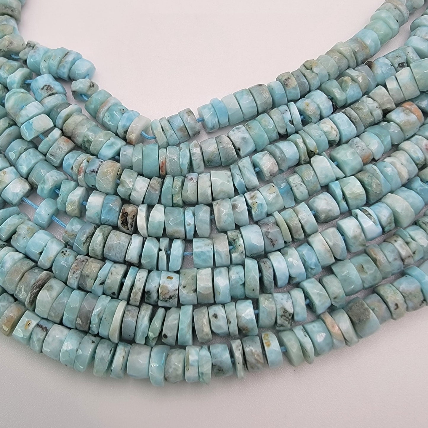 Larimar bead strands on a light gray background