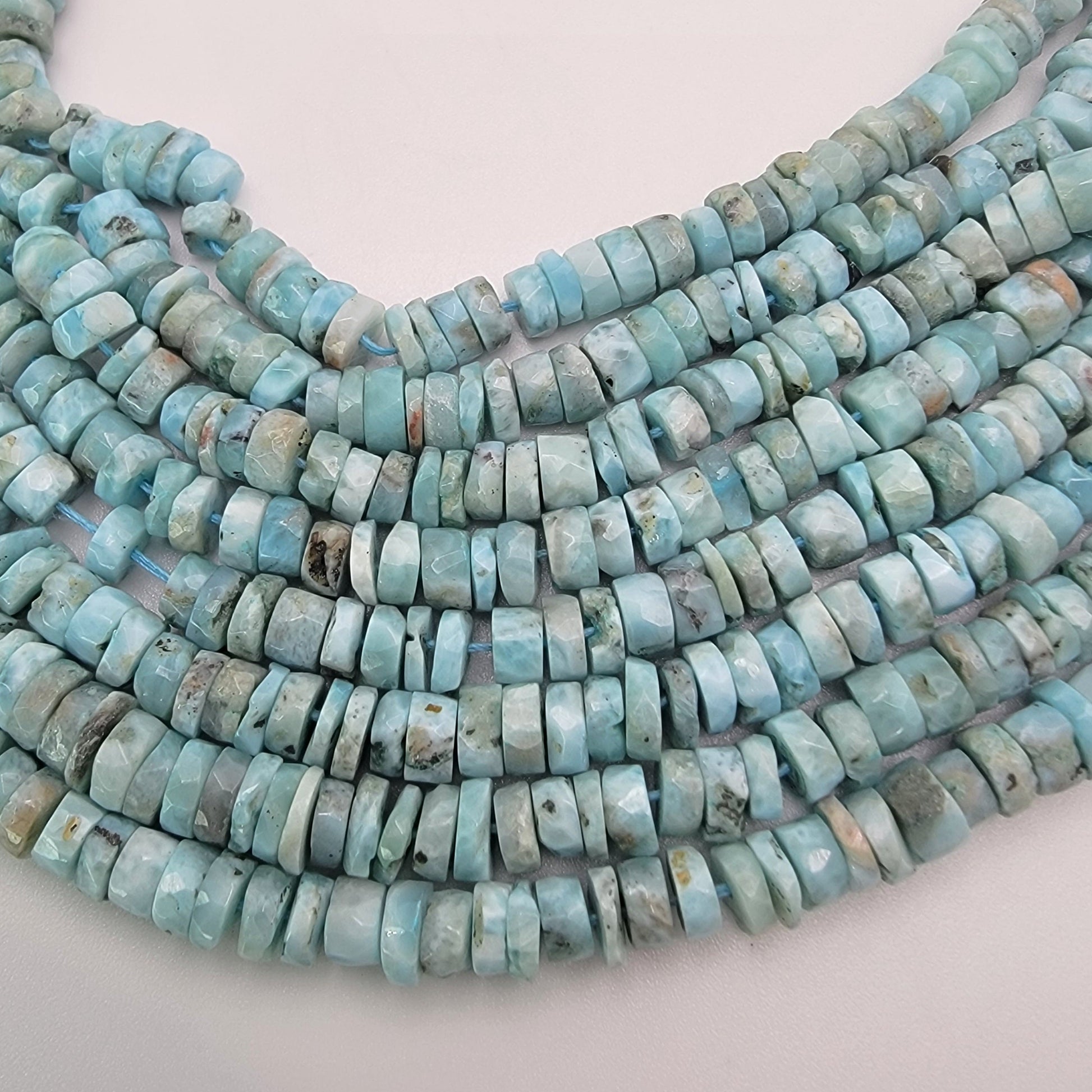 Larimar bead strands on a light gray background