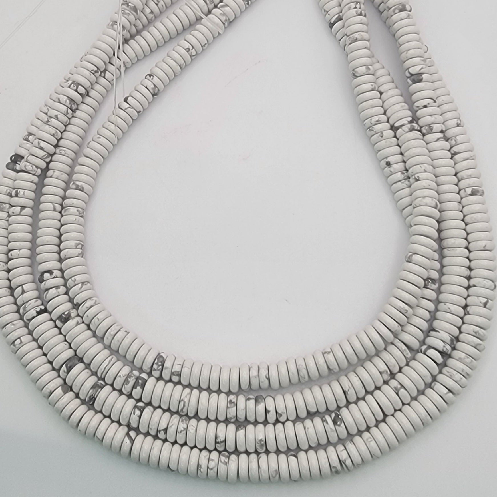 White stone bead strands on a light gray background