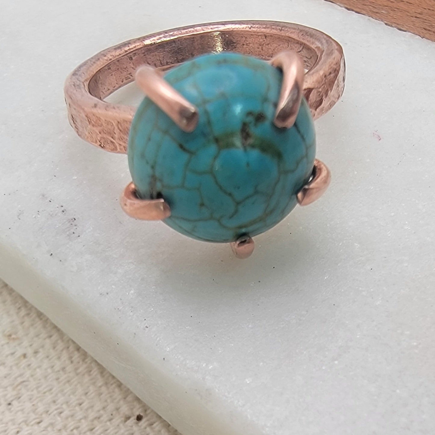 Ring with turquoise stone and copper band on a white surface