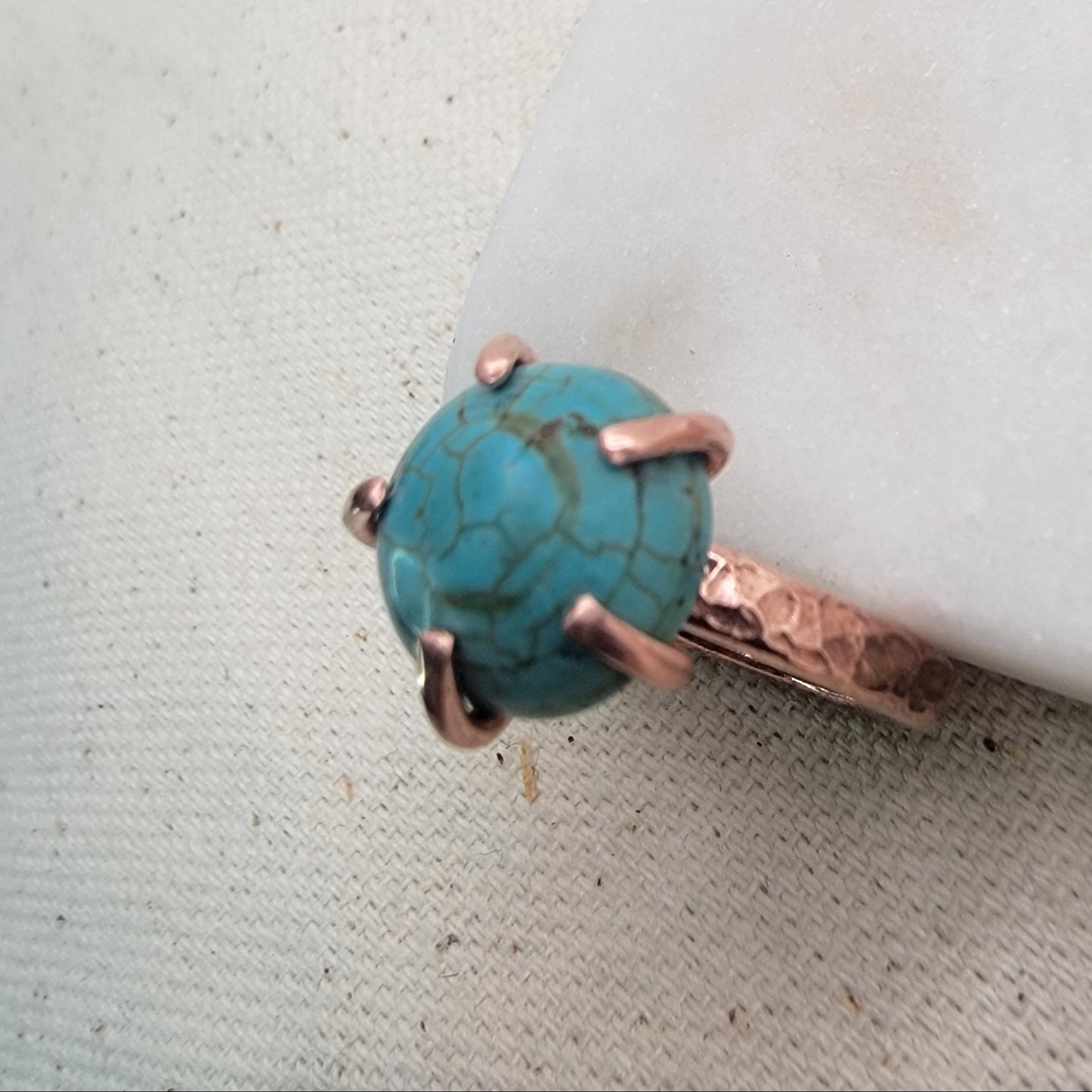 Turquoise ring with copper setting on a textured surface
