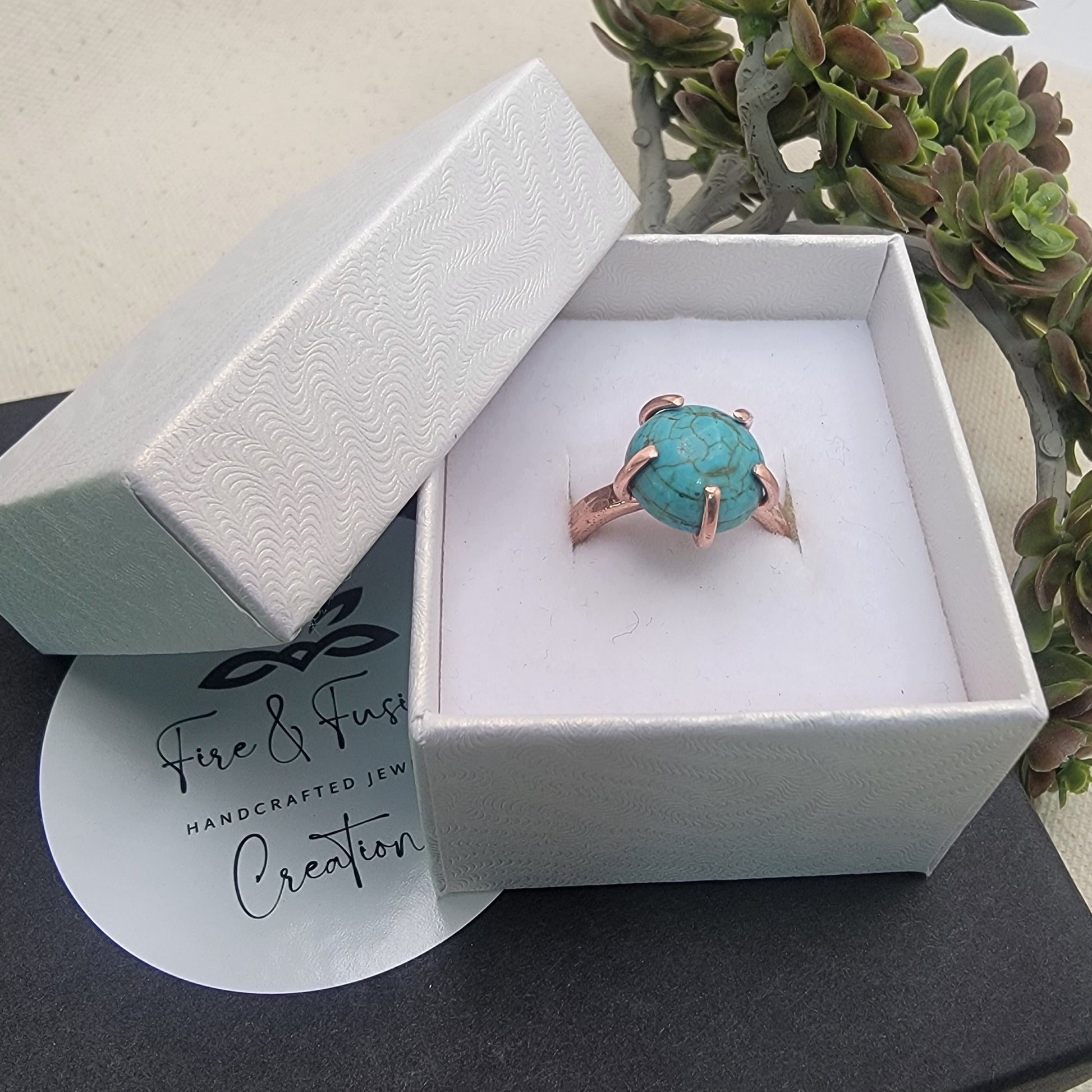 Turquoise ring in a white box with 'Fire & Fusion' branding, on a light background.