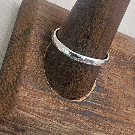 Silver ring on wood stand against neutral background