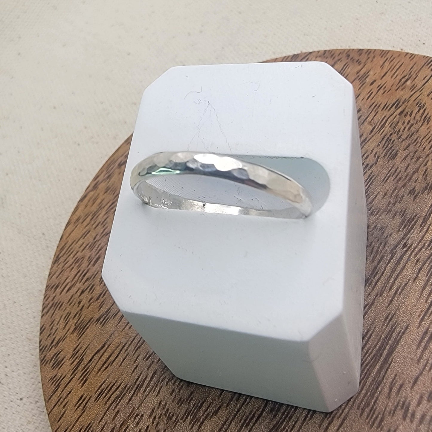 Silver ring on a white stand with a wooden surface