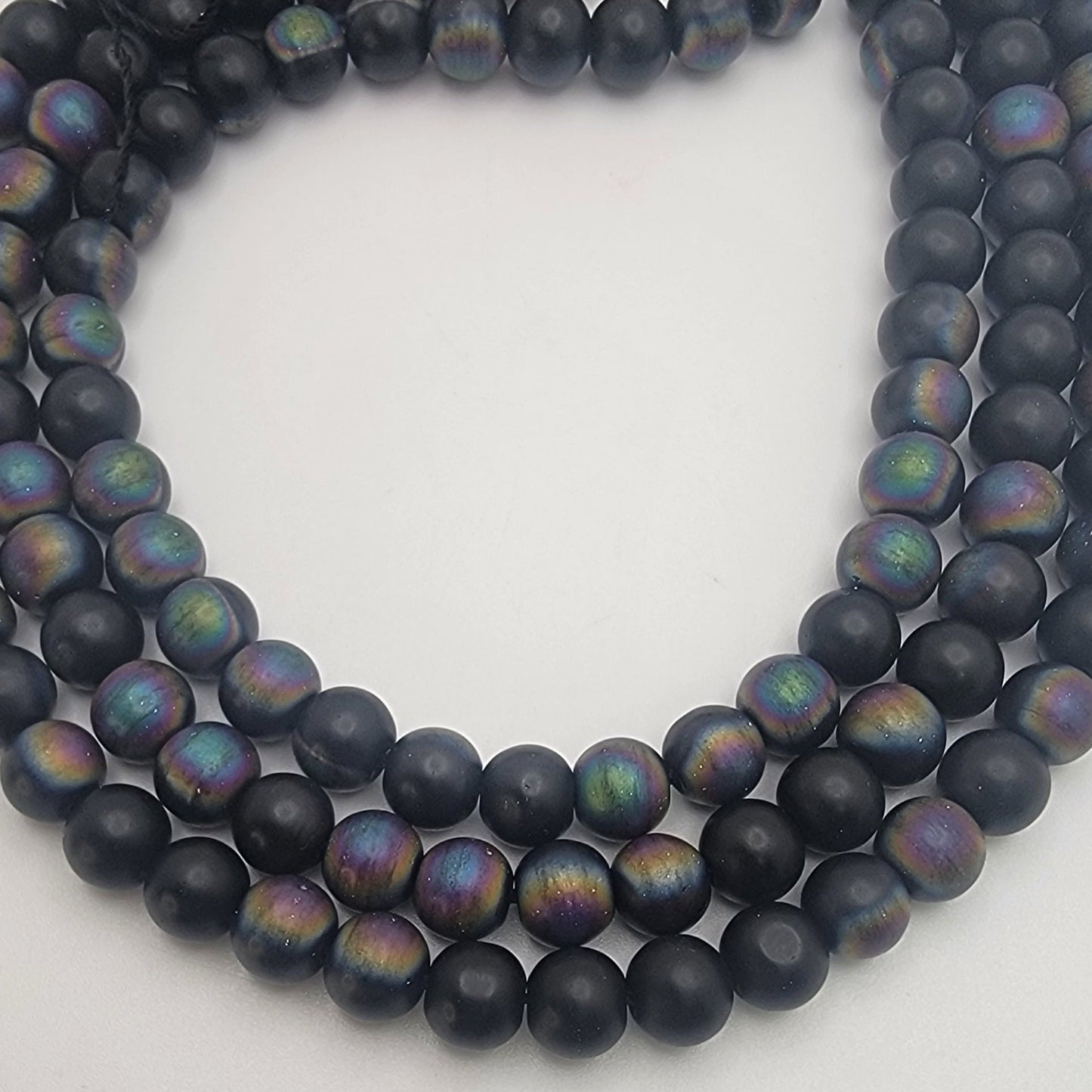 Black beads with rainbow iridescence on a white background