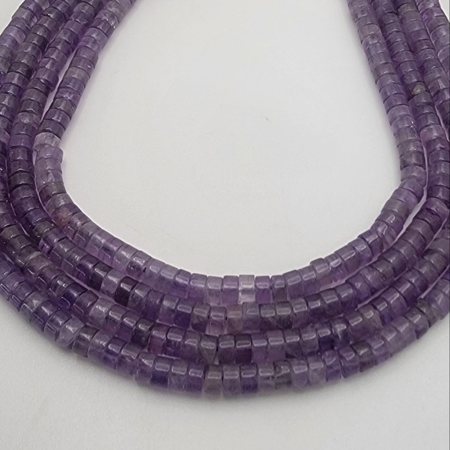Three strands of purple beads on a light gray background