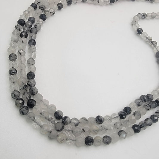Beaded  strand with alternating black and gray beads on a white background