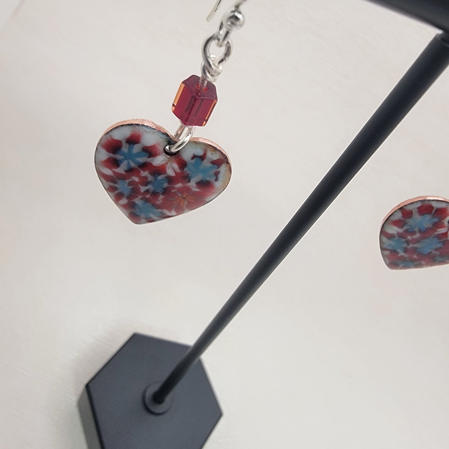 Earrings with floral design on a stand against a white background