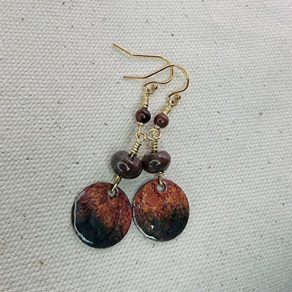 Pair of earrings with brown and gold accents on a textured gray background