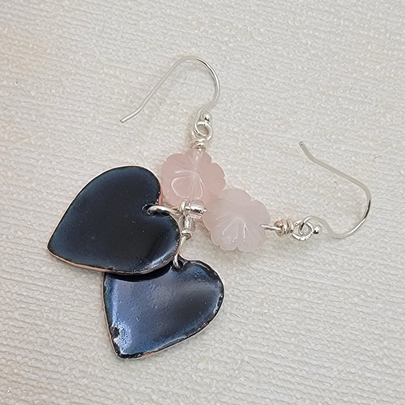 Heart-shaped earrings with pink and black stones on a light gray background