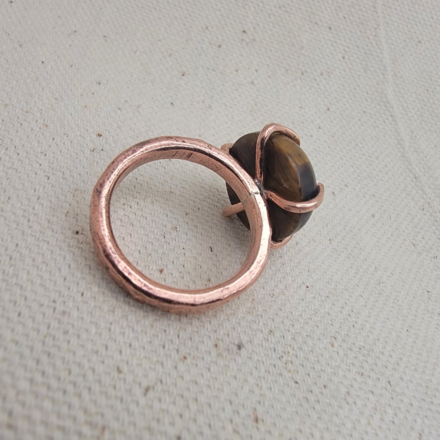 Copper ring with a brown stone on a textured gray background