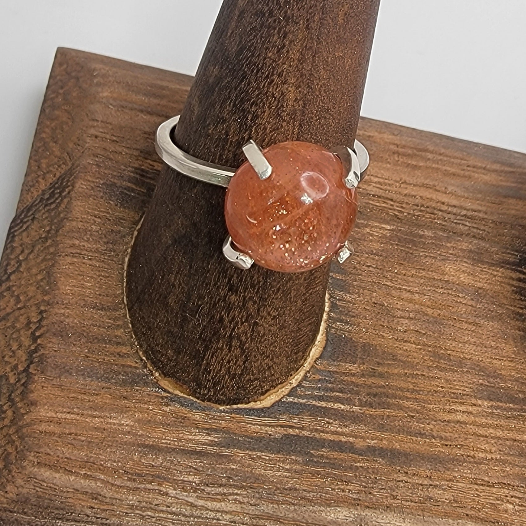 Ring with a brown stone on a wooden stand