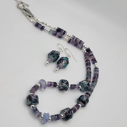 Jewelry set with purple and silver beads on a light gray background