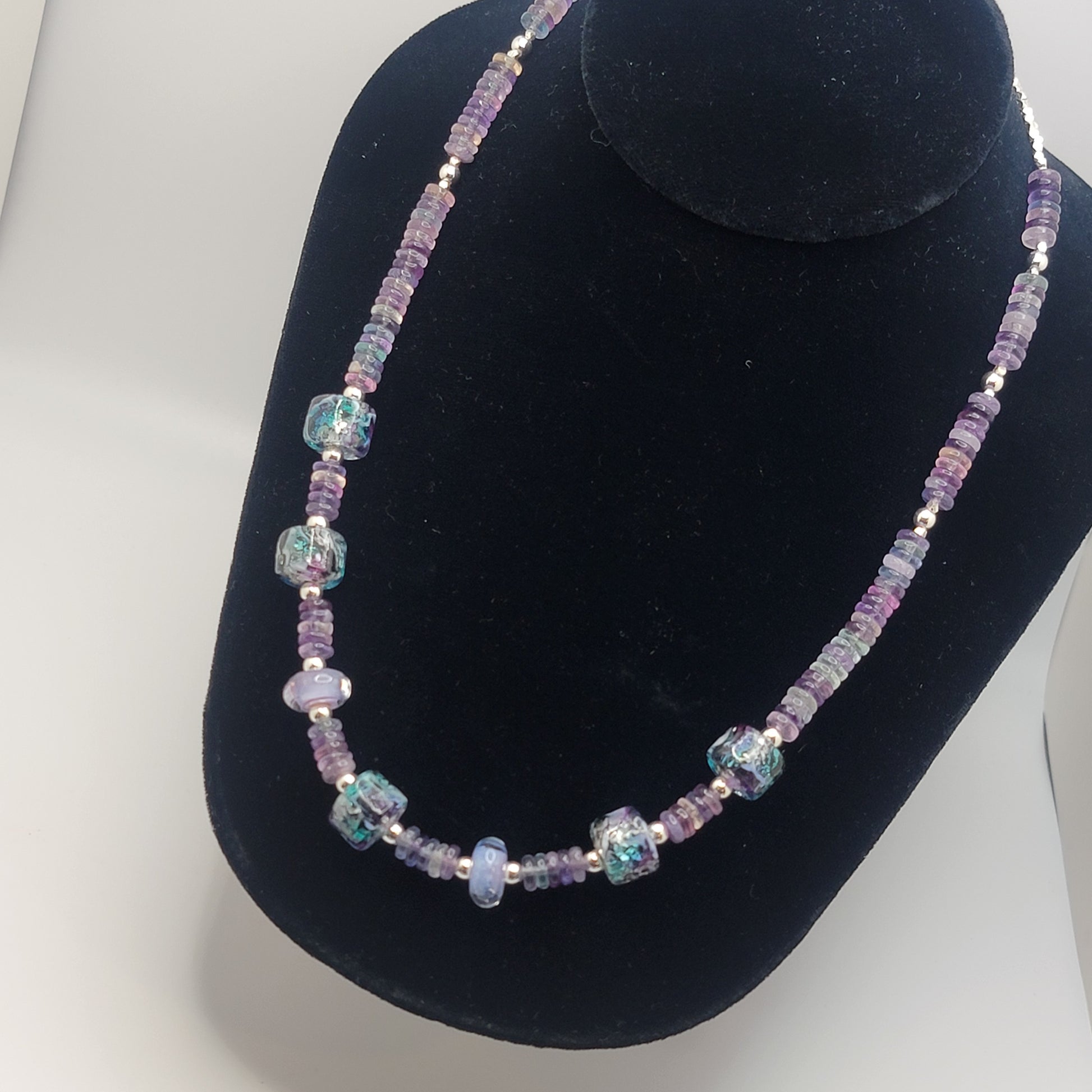 Necklace with purple and blue beads on a black velvet stand