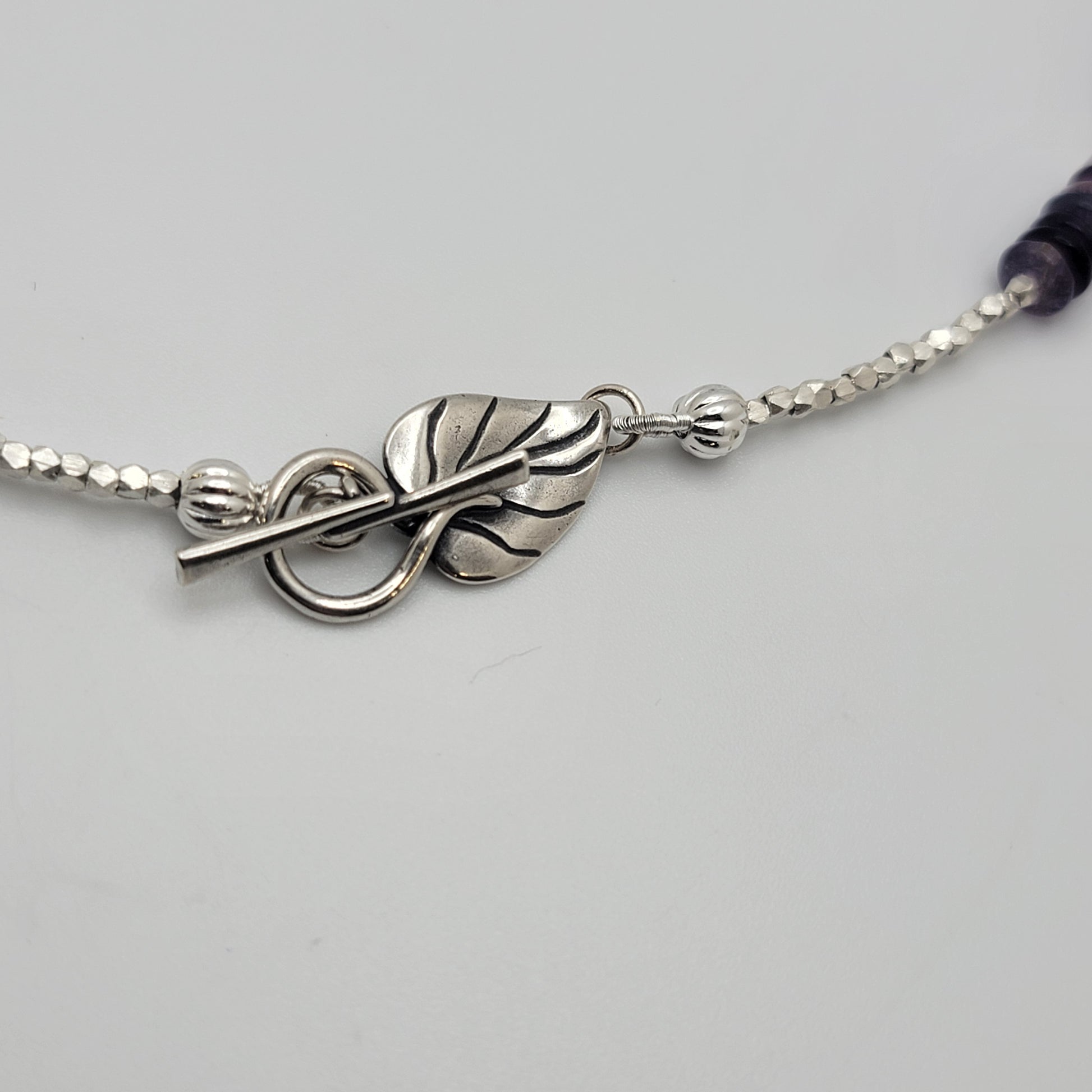 Silver bracelet with leaf design on a light gray background