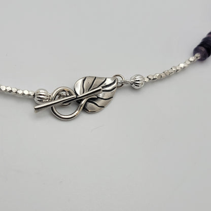 Silver bracelet with leaf design on a light gray background