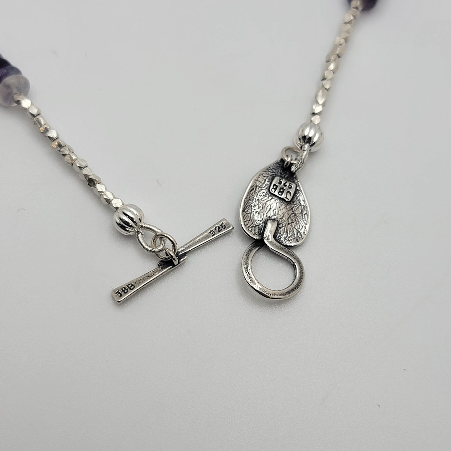 Silver necklace with a unique clasp on a light gray background