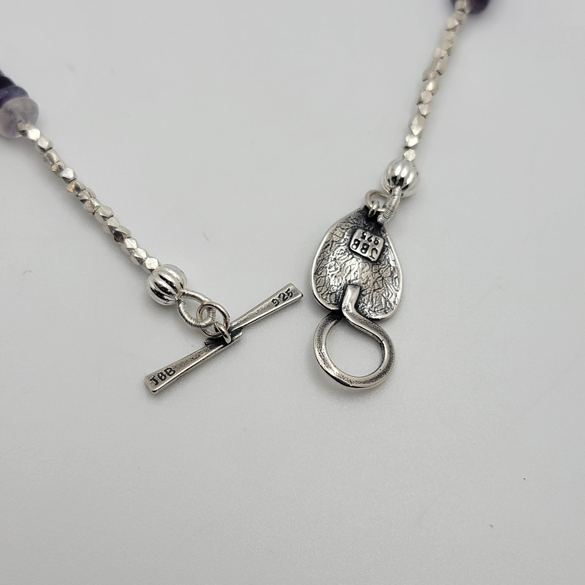 Silver necklace with a unique clasp on a light gray background
