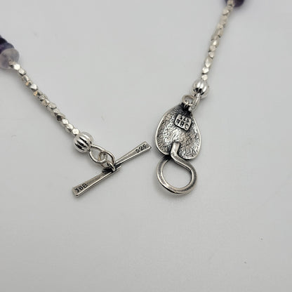 Silver necklace with a unique clasp on a light gray background